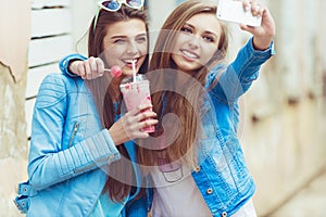 Hipster girlfriends taking a selfie in urban city