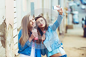 Hipster girlfriends taking a selfie in urban city