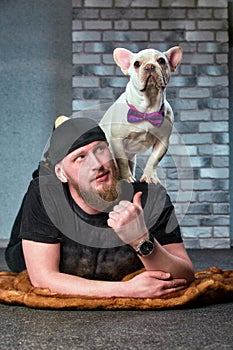 Hipster guy with his nice French Bulldog dogdressed in bow tie against brick wall on background. Pets love concept