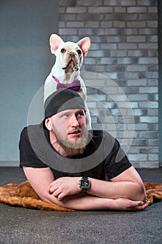 Hipster guy with his nice French Bulldog dogdressed in bow tie against brick wall on background. Pets love concept