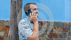 Hipster guy leaning in pole speaking by cellphone having a dialogue with his friend, consulting. Trendy person using telephone in