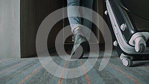 Hipster guy legs walking along hallway with suitcase. Man looking for hotel room