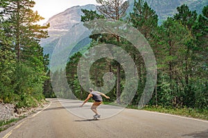 Hipster guy with long board with open arms enjoying life in the middle of a mountain road and a beautiful landscape.