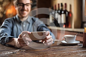 Hipster guy at the restaurant using a mobile phone