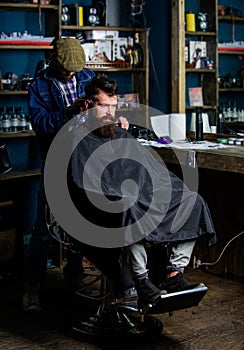 Hipster hairstyle concept. Hipster client getting haircut. Barber with clipper trimming hair on nape of client. Barber