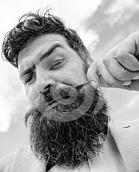 Hipster handsome attractive guy close up. Man bearded hipster twisting mustache sky background. Ultimate moustache