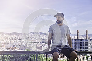 Hipster handsome male model with beard wearing gray blank t-shirt and a black snapback cap with space for your logo or