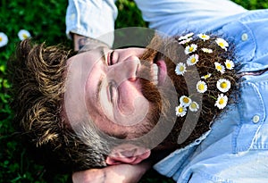Hipster on happy face lays on grass. Masculinity concept. Macho with beard and mustache enjoys spring, green meadow