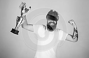 Hipster on happy face squeezing fist as successful gesture. Guy with head mounted display won in virtual game. Man with