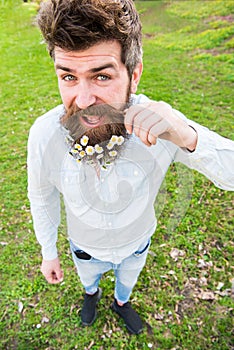 Hipster on happy face stand on grass, defocused. Natural beauty concept. Man with beard and mustache enjoy spring,twists