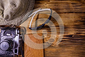 Hipster hat, vintage camera, sunglasses and passport on a wooden background. Top view