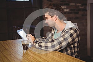 Hipster having coffee and using tablet computer