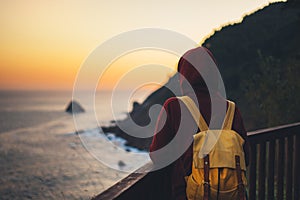 Hipster hiker tourist with backpack looking of amazing seascape sunset on background blue sea, girl enjoying ocean horizon, panora photo