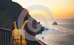 Hipster hiker tourist with backpack looking of amazing seascape sunset on background blue sea, girl enjoying ocean horizon, panora photo