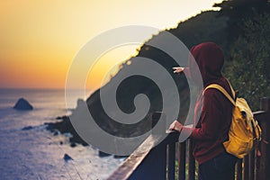 Hipster hiker tourist with backpack looking of amazing seascape sunset on background blue sea, girl enjoying ocean horizon, panora photo