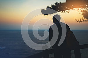 Hipster hiker tourist with backpack looking of amazing seascape sunset on background blue sea, guy enjoying ocean horizon, panoram