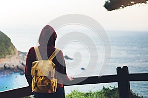Hipster hiker tourist with backpack looking on seascape sunset, background blue sea and mountain, girl enjoying ocean horizon