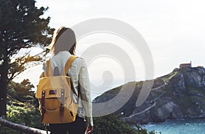 Hipster hiker tourist with backpack looking on seascape sunset, background blue sea and mountain, girl enjoying ocean horizon