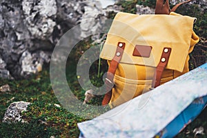 Hipster hiker tourist yellow backpack and map europe on background green grass nature in mountain, blurred panoramic landscape, tr