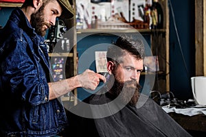 Hipster lifestyle concept. Barber with hair clipper works on hairstyle for bearded man barbershop background. Barber