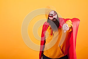 Hipster with long beard dressed in superhero costume looking away over yellow background