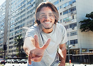 Hipster with long brunette hair showing victory sign in the city