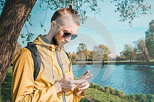 Hipster male touch mobile phone outdoor summer lifestyle in park