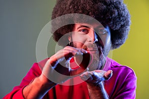 Hipster man with Afro hairstyle holding red toy heart, showing his fondness and devotion, romance. photo