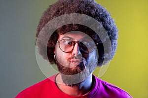 Hipster man with Afro hairstyle standing with crossed eyes and looking with funny comedian face.