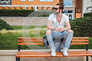 Hipster with man bun sitting on the park bench photo