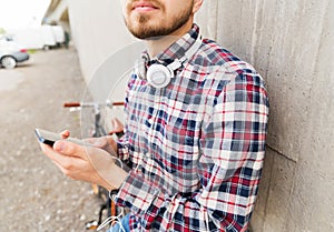 Hipster man in earphones with smartphone and bike