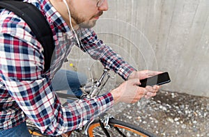 Hipster man in earphones with smartphone and bike