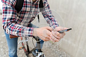 Hipster man in earphones with smartphone and bike