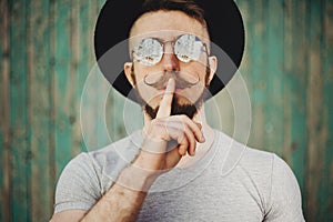 Hipster man gesture for silence showing hush sign