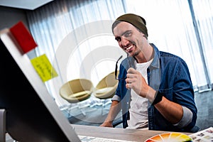 Hipster man holding glasses while working at computer desk