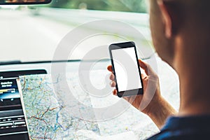 Hipster man looking on navigation map in car, tourist traveler driving and holding in male hands smartphone gps with clean screen