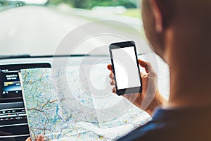 Hipster man looking on navigation map in car, tourist traveler driving and holding in male hands smartphone gps with clean screen