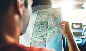 Hipster man looking and point finger on location navigation map in car, tourist traveler driving and hold in male hands europe car