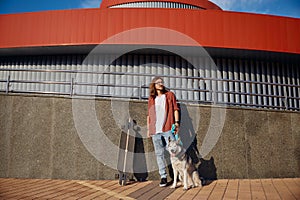 Hipster man riding skateboard with dog on leash enjoying summer time