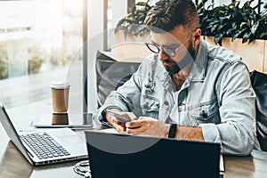 Bedrový muž sedí v kaviareň používa práce na dve notebooky. podnikateľ číta správa v telefón 