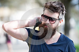 Hipster man with stylish beard and mustache walking in city. Closeup portrait of handsome young man in trendy eyewear