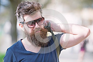 Hipster man with stylish beard and mustache walking in city. Closeup portrait of handsome young man in trendy eyewear