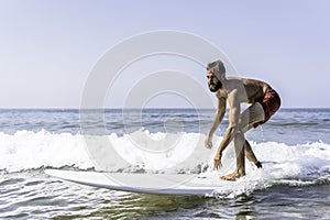 Hipster man surfing with a longboard on the waves - Fit guy training with a surfboard on a slightly rough sea - Water sport,