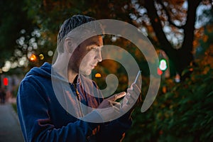 Hipster man talking on a mobile phone at night in the city against the background of bokeh lights.
