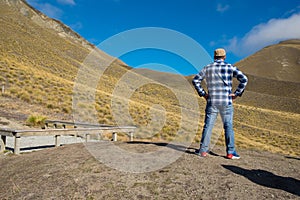 Hipster man traveller at yellow hill Lindis Pass, New Zealand.