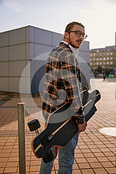 Hipster man wearing casual attire walking with skateboard