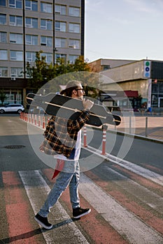 Hipster man wearing casual attire walking with skateboard