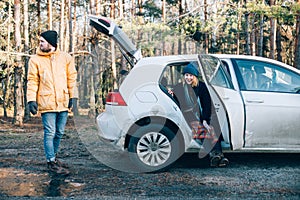 Couple next to small hybrid car in forest