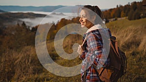 hipster millennial young woman walks on top of mountain summit at sunrise, looking ahead, enjoying beautiful view, happy