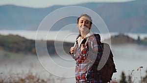 hipster millennial young woman walks on top of mountain summit at sunrise, looking ahead, enjoying beautiful view, happy